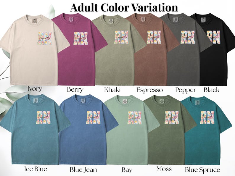 May include: A collection of short-sleeved t-shirts in various colors, including ivory, berry, khaki, and black. Each shirt features a colorful graphic design with the letters "RN" on the front. The text "Adult Color Variation" is at the top.