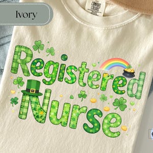 May include: Ivory t-shirt featuring the words "Registered Nurse" in green, adorned with shamrocks, a leprechaun's hat, a rainbow, and a pot of gold. The shirt is made of a soft material, ideal for St. Patrick's Day celebrations.