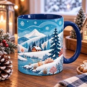 Peut inclure: Un mug en céramique avec une anse et un intérieur bleu foncé, illustré d'un paysage hivernal représentant un chalet enneigé, une rivière, des sapins et des montagnes lointaines sous un ciel bleu parsemé de flocons de neige blancs.
