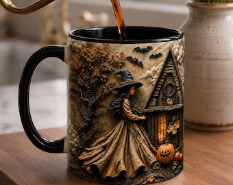 May include: A black-handled ceramic mug featuring a detailed illustration of a witch in a long dress standing near a wooden house with a glowing window, autumn trees, flying bats, and orange pumpkins, while dark liquid is poured into the top.