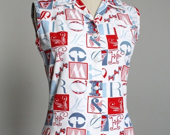 May include: A white sleeveless button-up shirt with a red, blue, and white patterned design featuring letters and swirls. The shirt has a collar and a "COLLAPSIBLE SHOULDER" label on the bottom.
