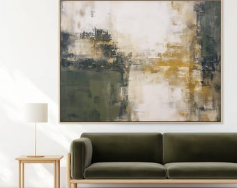 May include: Abstract art painting in a light wood frame. The artwork features a blend of olive green, white, and gold tones. The painting is displayed above a green velvet sofa and a small wooden side table with a lamp.