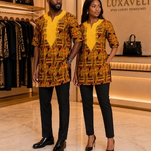 Peut inclure: Deux tuniques assorties présentant un motif géométrique vibrant dans des tons orange, vert et noir, rehaussées d'un col en V brodé jaune vif et de manches courtes, associées à un pantalon noir ajusté et des chaussures de ville noires.
