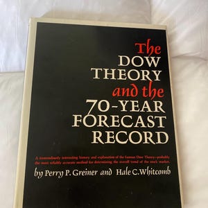 May include: A hardcover book titled "The DOW THEORY and the 70-YEAR FORECAST RECORD" with a black cover and white and red text. The book's cover also includes the names of the authors, Perry P. Greiner and Hale C. Whitcomb.