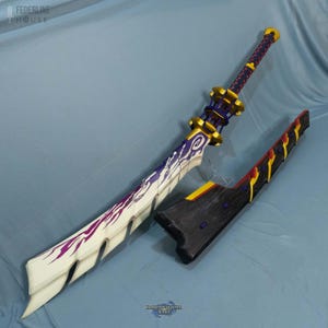 May include: A large, ornate sword with a white blade featuring purple and pink accents. The hilt is gold and purple, with a textured grip. A matching black sheath with yellow and red details lies beside it. The sword is a prop from the video game Monster Hunter Rise.