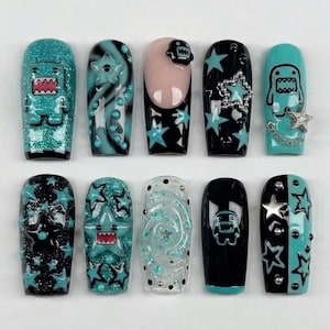 May include: A set of ten press-on nails featuring a black and teal color palette. Designs include 3D monster figures, star patterns, metallic studs, silver chains, and a clear swirl motif. The nails have a glossy finish with varied textures.