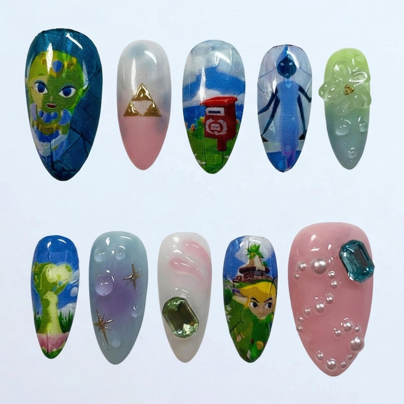 May include: A set of ten almond-shaped artificial nails, each with a unique design. The designs include cartoon characters, gold triangles, a red mailbox, and abstract patterns. Colors include blue, pink, green, and white.