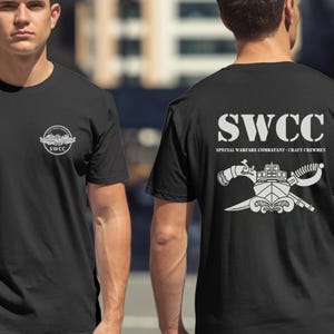 May include: Black t-shirts with white graphics. One shirt features a small emblem with the text "SWCC". The other shirt displays "SWCC" in large letters, along with "SPECIAL WARFARE COMBATANT - CRAFT CREWMEN" and a detailed emblem.