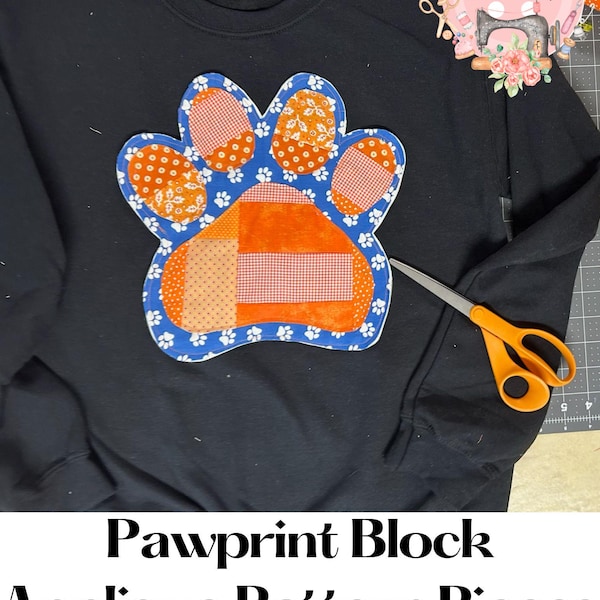 May include: A black sweatshirt with a paw print applique made from orange, white, and blue fabric. The paw print is made up of several smaller fabric squares sewn together. The text "Pawprint Block Applique Pattern Pieces" is at the bottom of the image.