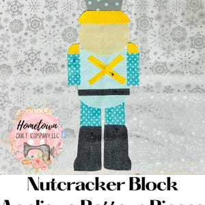 May include: A Nutcracker Block Applique Pattern Pieces sewing pattern. The pattern pieces are laid out on a white fabric with a snowflake pattern. The pattern pieces are in various colors, including blue, yellow, gray, and black.