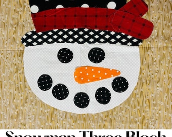 May include: A three-block snowman applique pattern with black and white polka dot hat, red and white plaid band, black and white checkered scarf, white face with black eyes, black buttons, and an orange carrot nose.