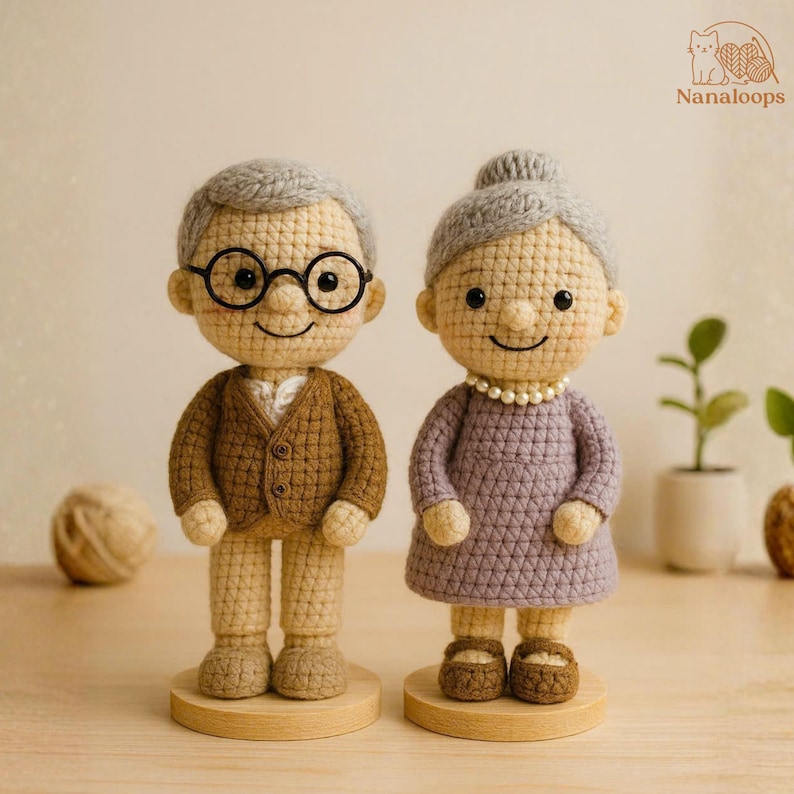 K&ouml;nnte beinhalten: Geh&auml;kelte Puppen eines &auml;lteren Ehepaares. Die m&auml;nnliche Puppe tr&auml;gt eine braune Jacke, eine Brille und ein wei&szlig;es Hemd. Die weibliche Puppe tr&auml;gt ein lila Kleid und eine Perlenkette. Beide Puppen haben graues Haar und stehen auf Holzsockeln.