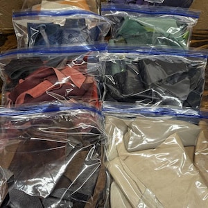 May include: Ten clear plastic bags filled with various colors and textures of leather scraps. The bags are sealed with blue zipper closures.