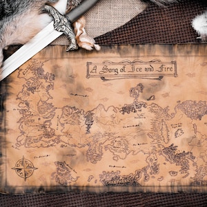 May include: A vintage-style map of Westeros, the fictional continent from the book series "A Song of Ice and Fire", with the title "A Song of Ice and Fire" printed at the top. The map is on a brown background with a sword and a fur pelt.