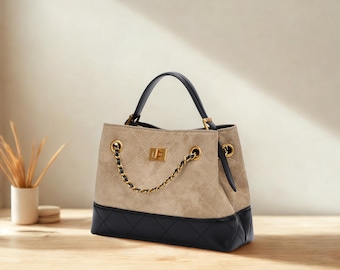 Bolsa de mão bicolor em couro vegano com detalhe em corrente dourada.
