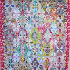 May include: A colorful quilt with a geometric pattern of repeating starbursts. The quilt is made of various fabrics in shades of pink, blue, green, yellow, and white. The quilt is bordered with a solid pink fabric.