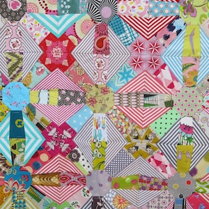 May include: A colorful patchwork quilt with a variety of geometric patterns. The quilt features diamonds, stripes, and floral designs in shades of pink, blue, green, and red. The quilt is made of fabric squares sewn together.