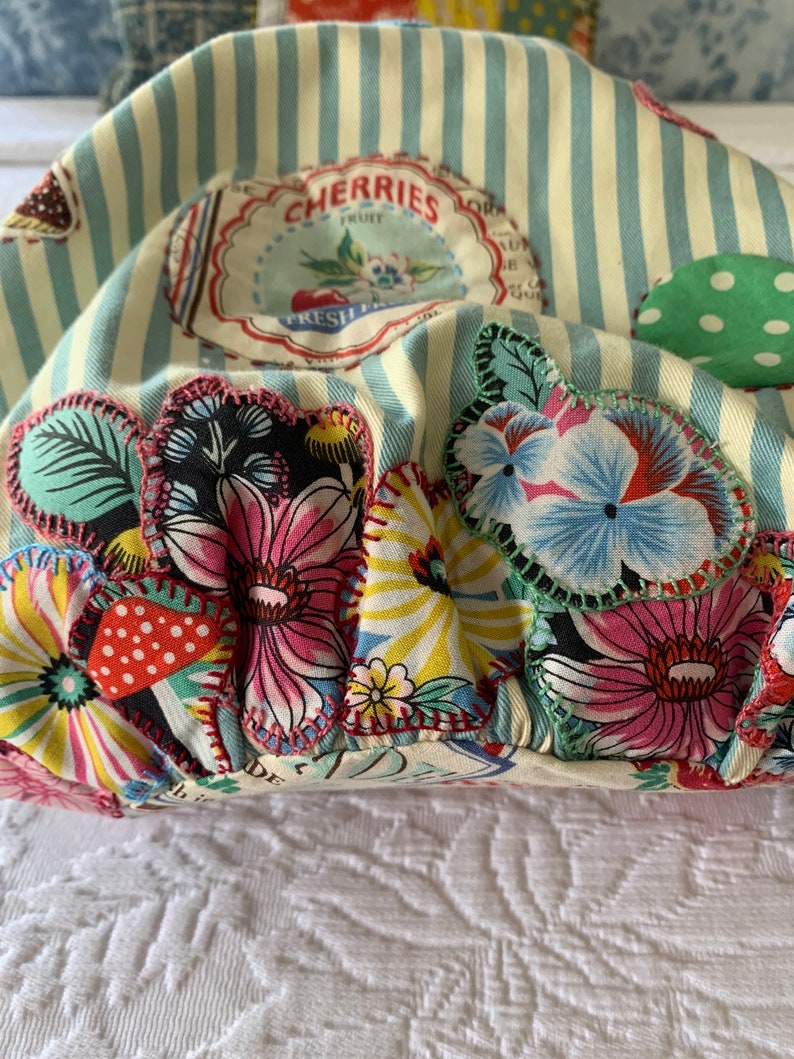 May include: A yellow and blue striped fabric bag with a variety of colorful floral and polka dot patches. The bag has a label that reads "Cherries Fruit Fresh From".