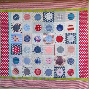 May include: A patchwork quilt with a white background and a grid of colorful circles. The circles are in shades of red, blue, and white and feature various patterns, including polka dots, stripes, and floral designs.