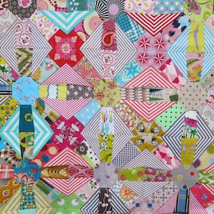 May include: A colourful patchwork quilt featuring a range of geometric patterns and bright colours, including pink, red, blue, green, yellow and white.
