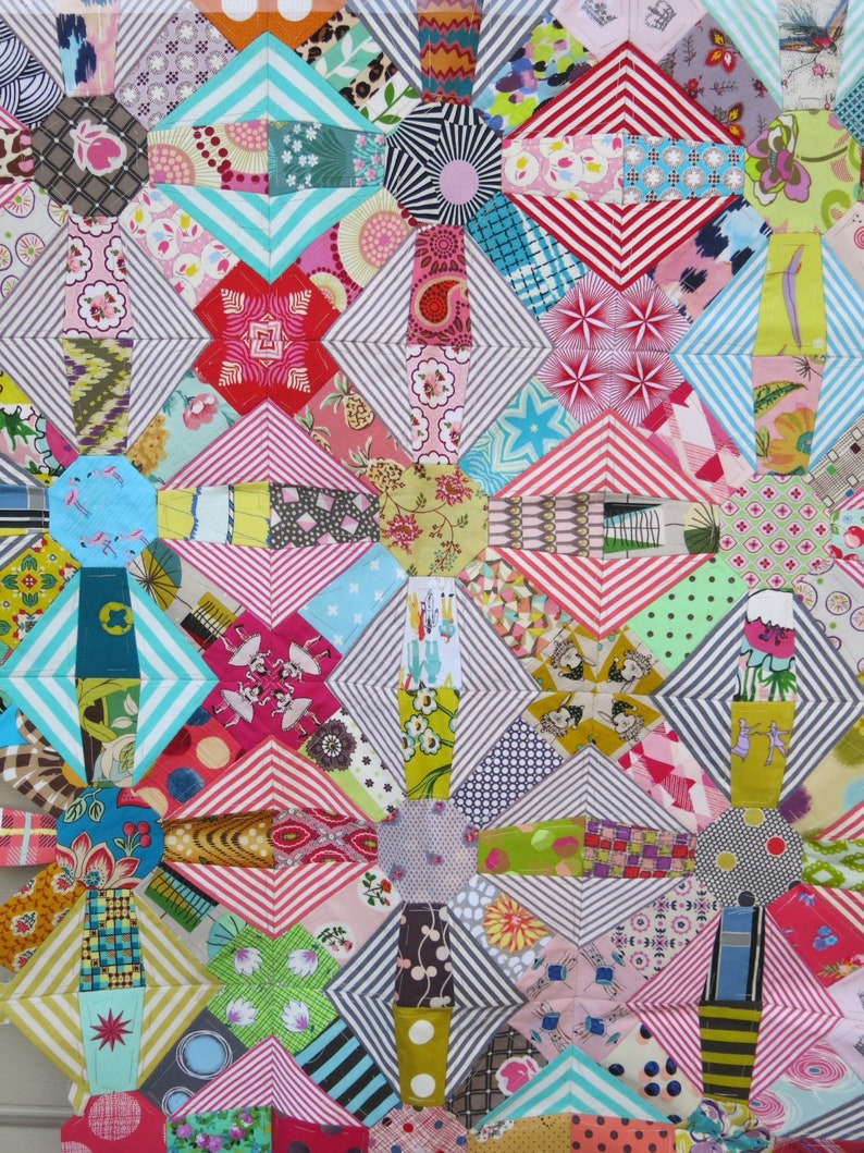 May include: A colourful patchwork quilt featuring a range of geometric patterns and bright colours, including pink, red, blue, green, yellow and white.