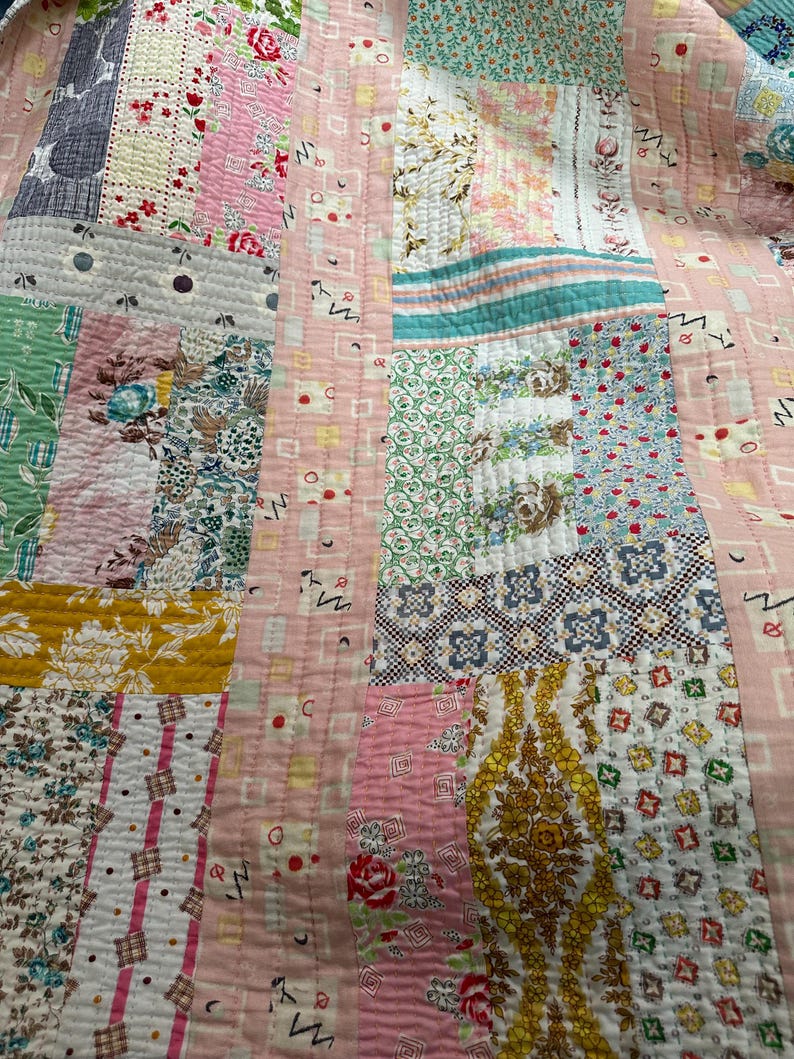 Puede incluir: Una colcha de retazos hecha con diferentes telas con estampados florales en tonos rosa, verde, azul y amarillo. La colcha est&aacute; cosida con hilo blanco y tiene una textura acolchada.