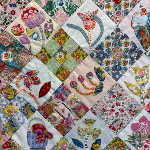 May include: A quilt with a patchwork design featuring a variety of floral patterns in shades of pink, blue, green, and yellow. The quilt is titled "Calico Garden: Take an Element" by Margaret Sampson George.