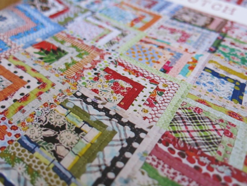 May include: A patchwork quilt with a variety of colorful fabrics, including red, green, blue, and white. The quilt is made up of squares and rectangles, and the fabric is sewn together in a random pattern.