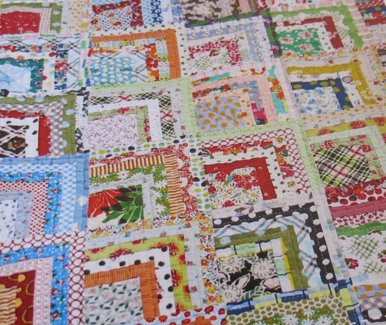 May include: A colorful quilt made with a patchwork of fabric squares. The squares are arranged in a pattern of overlapping squares, creating a layered effect. The quilt is made with a variety of fabrics, including floral prints, geometric patterns, and solid colors.