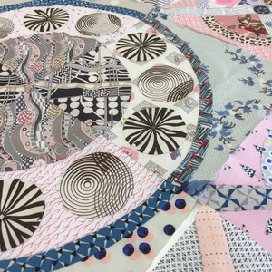 May include: A close-up of a quilt with a variety of colorful fabrics and patterns. The quilt features a circular design with a blue border and a white center. The center of the quilt is filled with a variety of geometric shapes and patterns, including circles, squares, and triangles. The quilt is made up of a variety of fabrics, including cotton, silk, and velvet.