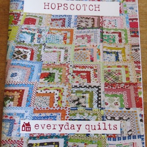 May include: A book cover with a colorful patchwork quilt design. The title "HOPSCOTCH" is printed in white on a white label. The text "everyday quilts" is printed in white on a red label with a small house icon.