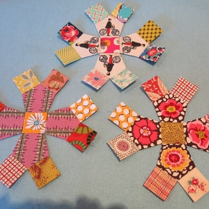 May include: Three colourful fabric starburst shapes with a variety of patterns and colours, including pink, red, yellow, green, blue and white.