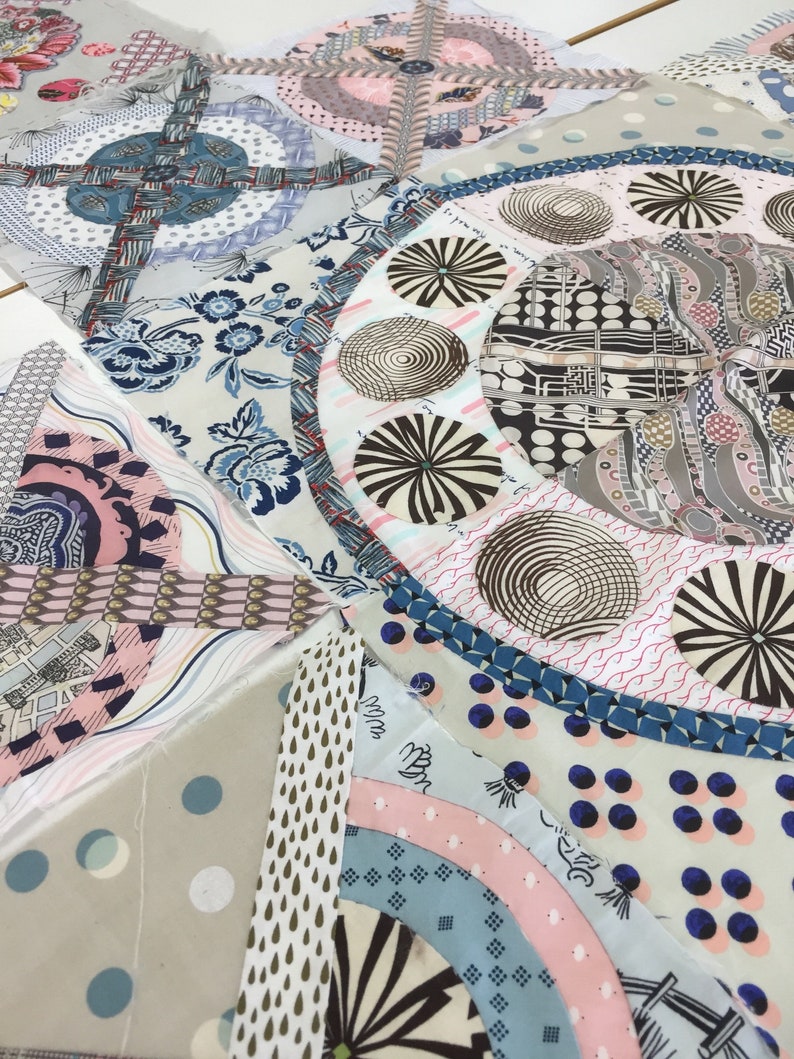 May include: A close-up of a quilt made of various fabrics with different patterns. The quilt is made up of many different shapes and sizes, and the fabrics are all different colors. The quilt is a patchwork of different fabrics, and the colors are bright and vibrant.