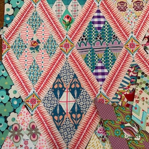 May include: A patchwork quilt with a diamond pattern in shades of pink, blue, green, and white. The quilt is made of various fabrics with different patterns and textures.
