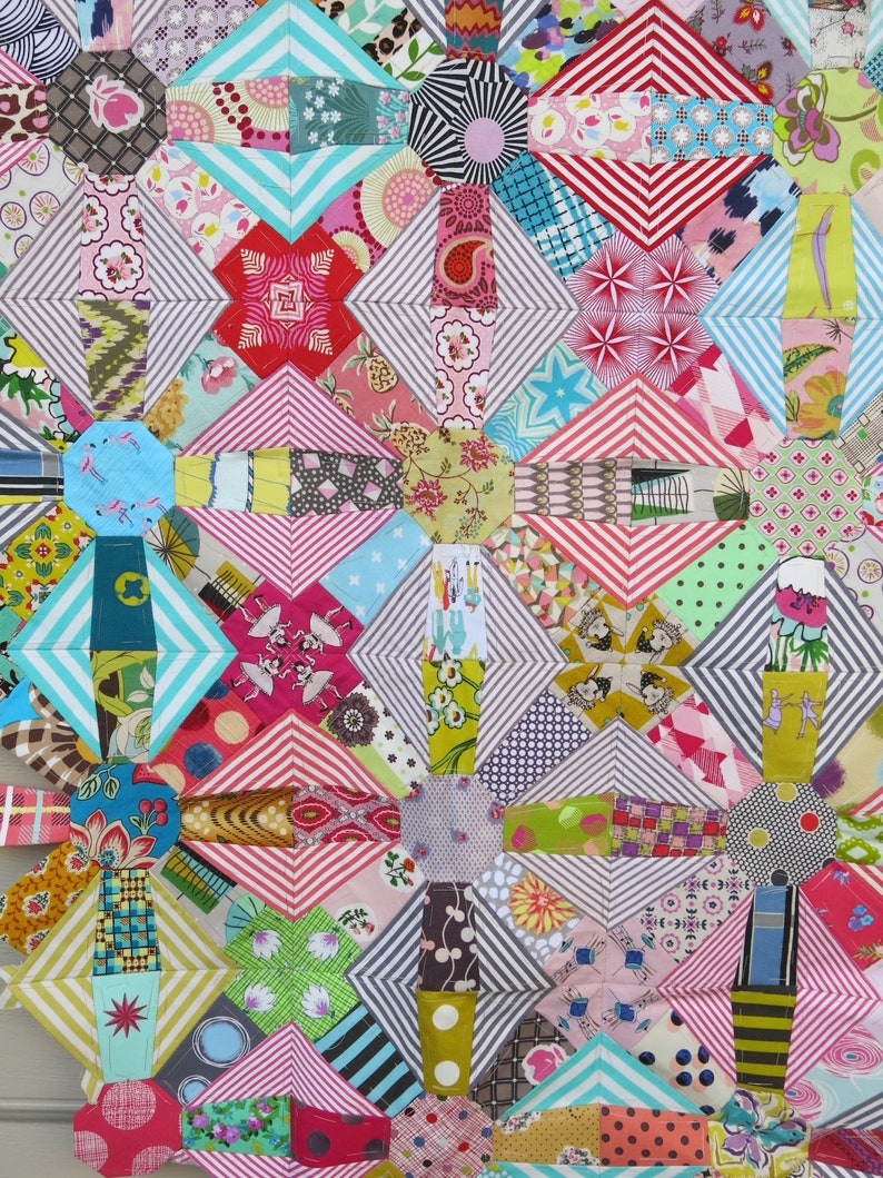 May include: A colourful quilt made of various patterned fabrics. The quilt is made up of a variety of geometric shapes, including squares, triangles, and diamonds. The quilt is a mix of bright colours, including red, pink, blue, green, and yellow.