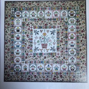 May include: A quilt pattern titled "Threadneedle Street" featuring a floral design with a central motif of a flower pot with a variety of flowers and leaves. The quilt is made up of a patchwork of different fabrics with a variety of colours and patterns. The quilt is surrounded by a border of small floral motifs.