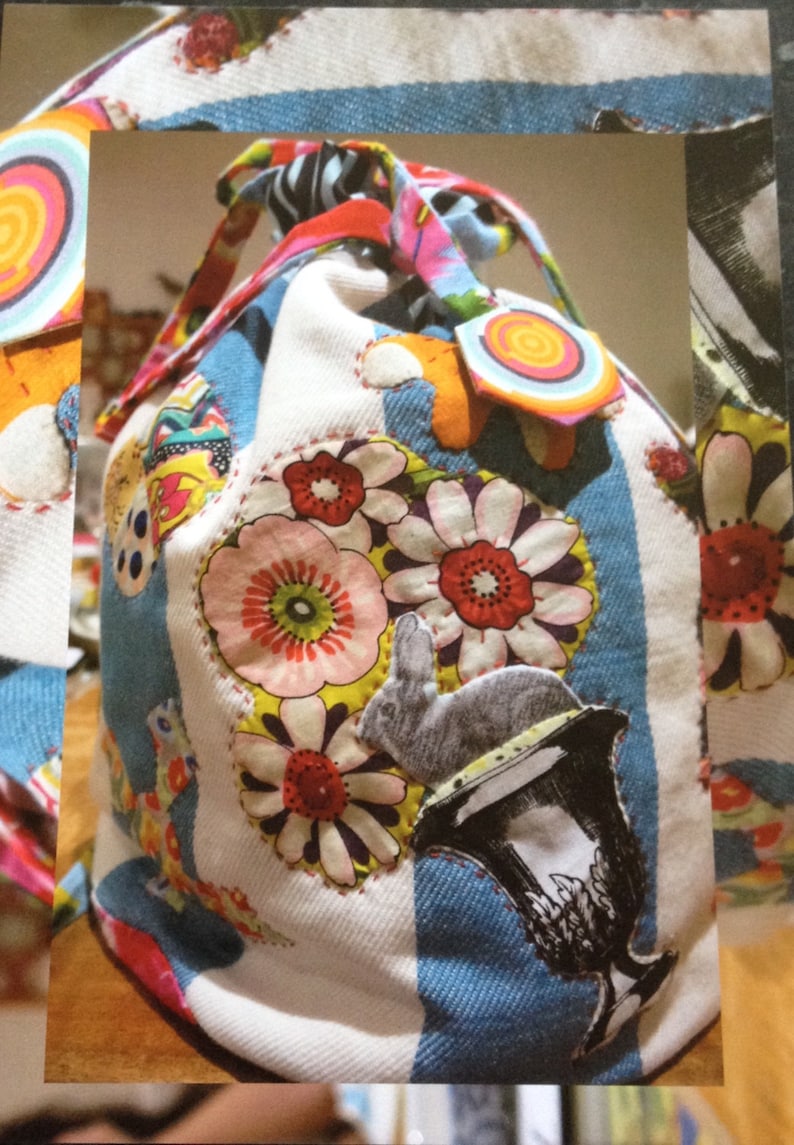 May include: A white fabric bag with a drawstring closure. The bag is decorated with colorful fabric scraps, including flowers, a rabbit, and a cup. The bag is made of a patchwork of different fabrics.