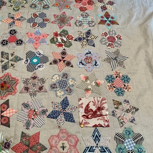 May include: A quilt in progress with a variety of colorful fabric squares sewn together in a star pattern. The quilt is made with a variety of floral and geometric prints.