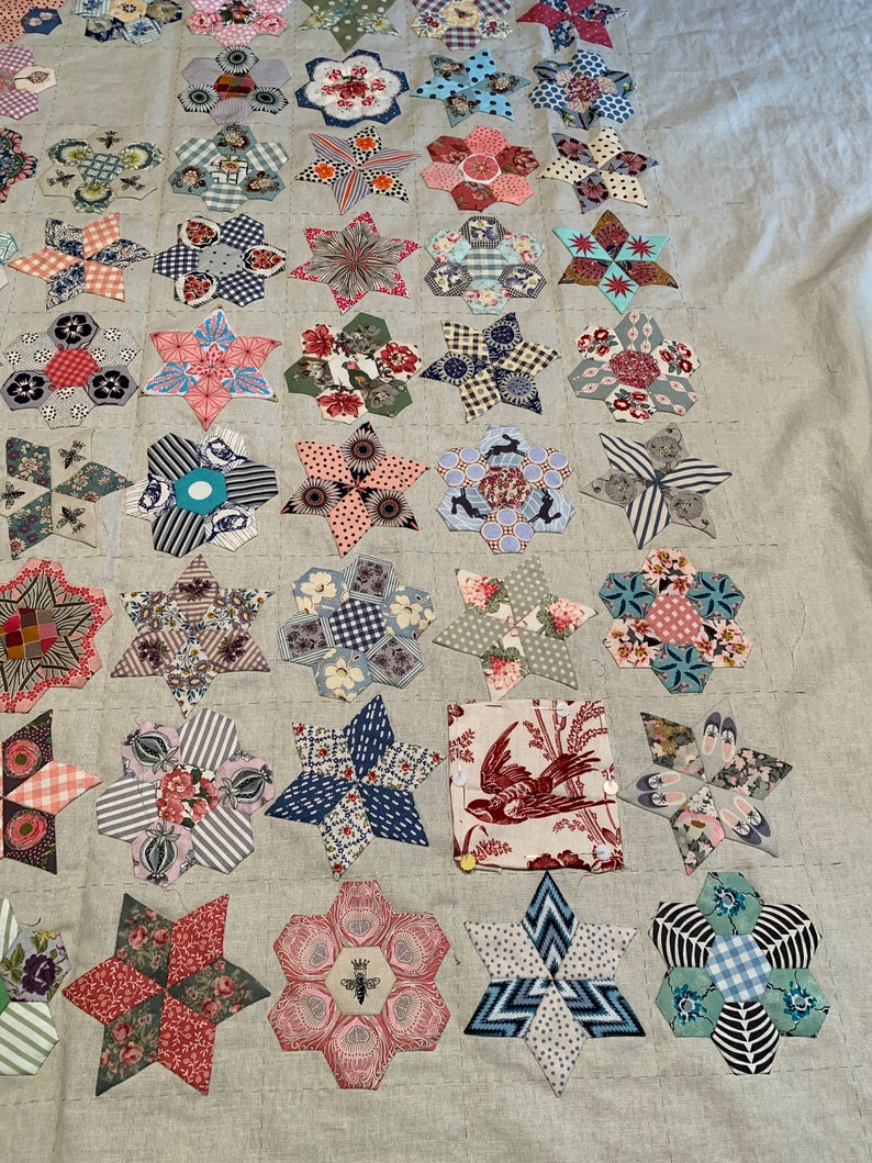May include: A quilt in progress with a variety of colorful fabric squares sewn together in a star pattern. The quilt is made with a variety of floral and geometric prints.