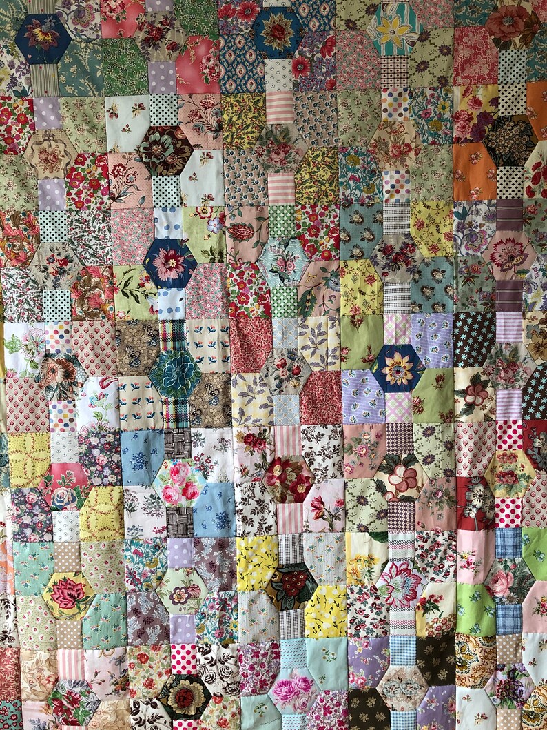 K&ouml;nnte beinhalten: Eine Decke aus bunten Stoffquadraten mit Blumenmustern. Die Decke besteht aus einem sich wiederholenden Muster aus Sechsecken und Quadraten.