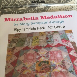 May include: A quilt pattern called "Mirrabella Medallion" by Marg Sampson-George. The pattern includes a template pack and a 1/4" seam allowance. The quilt is made of colorful fabric with floral patterns.