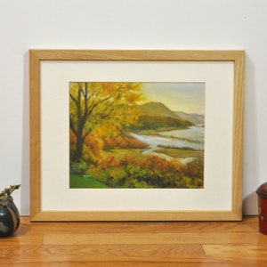 Puede incluir: Pintura enmarcada de una escena de paisaje con un r&iacute;o serpenteando por un valle con follaje oto&ntilde;al. La pintura est&aacute; en un marco de madera claro.