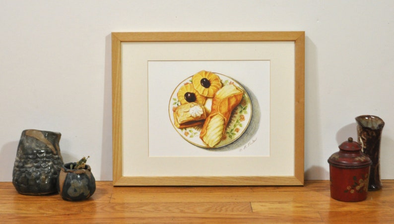 May include: A framed watercolor painting of a plate of pastries. The plate is white with a floral pattern and contains three pastries: a puff pastry, a cannoli, and a cookie. The pastries are all yellow and brown.