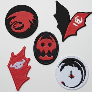 May include: Set of five embroidered patches featuring dragon-themed designs. Includes a round black patch with a red dragon, a black and red bat-wing patch with a skull, and a red shield-shaped patch with a white skull.