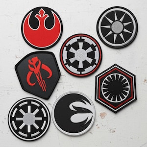 May include: A collection of embroidered patches featuring various symbols in black, red, and white. The patches include circular, shield, and hexagonal shapes, with detailed designs representing different factions.