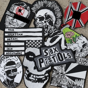 May include: A collection of embroidered patches with punk rock and anti-establishment themes. Designs include a skull with a mohawk, the American flag with the text "Your American Dream Is Our Nightmare," and the words "Sex Pistols."