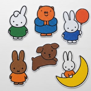 May include: Set of six embroidered patches featuring cartoon characters. Includes a white bunny in a green shirt, an orange pig in a blue outfit, a white bunny with a red balloon, a brown bunny in an orange shirt, a brown dog, and a white bunny on a yellow crescent moon.