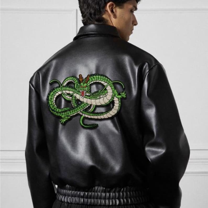 May include: Black leather jacket with a green and gold embroidered dragon design on the back. The jacket has a classic collar and a ribbed hem. The dragon is a detailed, stylized representation.