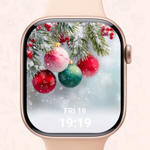 May include: A gold smartwatch displaying a Christmas scene with baubles, snowy branches, and berries. The screen shows the date and time: FRI 19, 19:19. The watch has a light pink strap. The overall theme is festive.