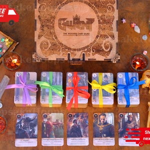 Może przedstawiać: Drewniane pudełko z napisem "Gwent The Witcher Card Game" i kilka talii kart związanych kolorowymi wstążkami. Obraz zawiera również zapalone świece, dekoracyjne gwiazdki i małe drewniane pudełko wypełnione gwiazdkami origami.